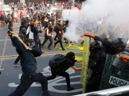 La policía encapsuló a un grupo de anarquistas, que terminaron por entregar una bolsa con cadenas y petardos para poder seguir avanzando. EFE/C. Ramírez