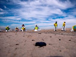 Trabajadores recogen chapopote de la playa de Huntington Beach, California, luego del derrame de petróleo. EFE/E. Laurent