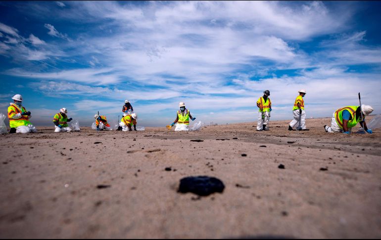 Trabajadores recogen chapopote de la playa de Huntington Beach, California, luego del derrame de petróleo. EFE/E. Laurent