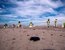 Trabajadores recogen chapopote de la playa de Huntington Beach, California, luego del derrame de petróleo. EFE/E. Laurent