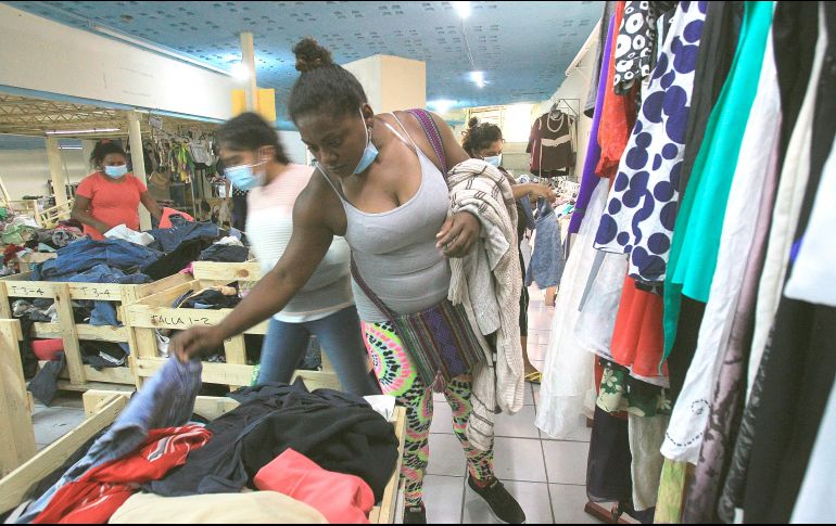 Migrantes varados en Ciudad Juárez, en espera de que Estados Unidos defina sus solicitudes de asilo, escogen ropa usada que fue donada por activistas. EFE/L. Torres