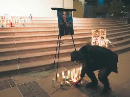 Recuerdo. Un hombre coloca una veladora en un altar improvisado en honor a Halyna Hutchins, en Albuquerque, Nuevo México. AP