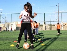 Usando petos coloridos, las niñas hacen ejercicios de estiramiento en el césped antes de que Yusef Chaba sople el silbato para comenzar la práctica. AFP/Z. Al Obeidi
