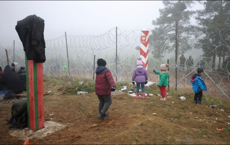 Migrantes se ven cerca de una malla en Polonia, cerca de la frontera con Grodno, Bielorrusia. AP/BelTA/L. Shcheglov