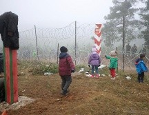 Migrantes se ven cerca de una malla en Polonia, cerca de la frontera con Grodno, Bielorrusia. AP/BelTA/L. Shcheglov