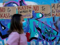 Una mujer pasa junto a carteles contra el candidato presidencial chileno José Antonio Kast. AFP/M. Bernetti