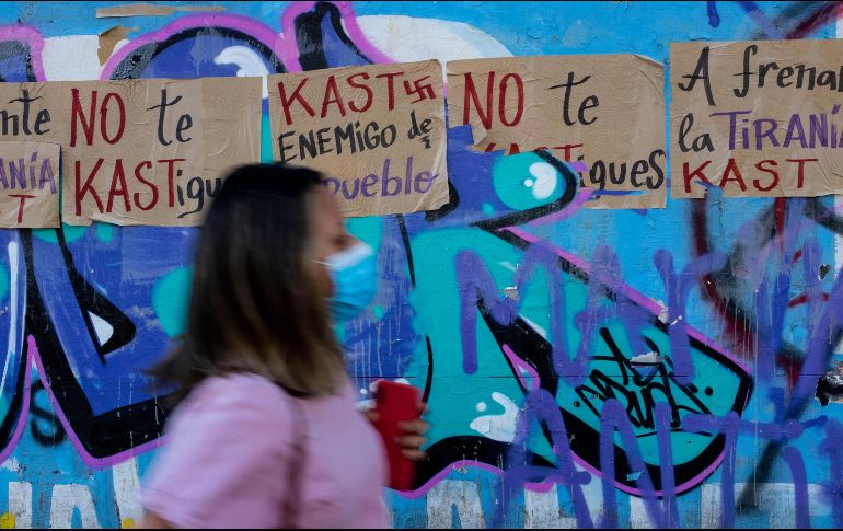 Una mujer pasa junto a carteles contra el candidato presidencial chileno José Antonio Kast. AFP/M. Bernetti
