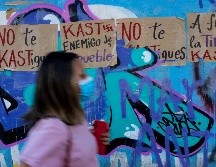 Una mujer pasa junto a carteles contra el candidato presidencial chileno José Antonio Kast. AFP/M. Bernetti