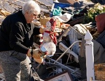 Una mujer rescata un adorno navideño de entre los escombros de su vivienda destrozada, en Mayfield. AP/G. Herbert
