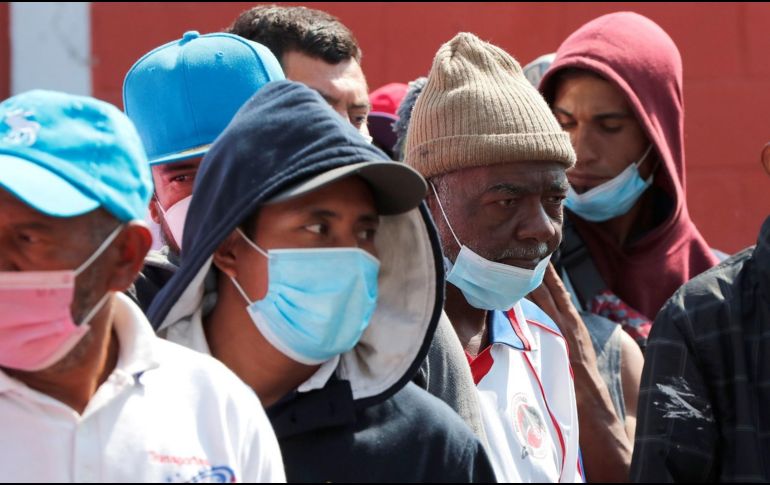 Migrantes con cubrebocas hacen fila para recibir sus alimentos en el albergue la Casa del Peregrino, en la Basílica de Guadalupe. EFE/J. Méndez