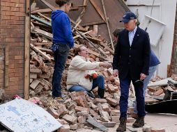 Con una gorra de béisbol y un traje sin corbata, el presidente estrechó la mano de una mujer sentada entre los escombros de un edificio derrumbado. AP/A. Harnik