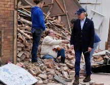 Con una gorra de béisbol y un traje sin corbata, el presidente estrechó la mano de una mujer sentada entre los escombros de un edificio derrumbado. AP/A. Harnik