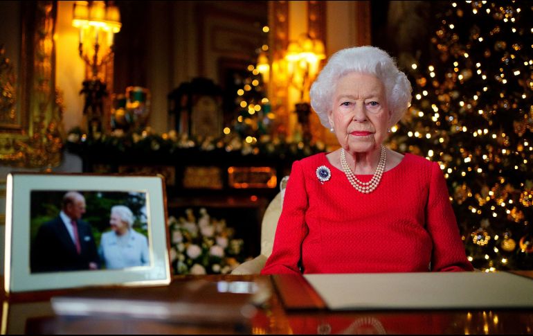 La reina Isabel II apareció con un vestido rojo, sentada junto a una fotografía de 2007 en la que ella y su marido se miran y se sonríen, tomada durante sus bodas de diamante (60 años de matrimonio). AFP