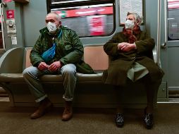 Una pareja de la tercera edad protegida con cubrebocas viaja en el metro de Milán. AFP/M. Medina