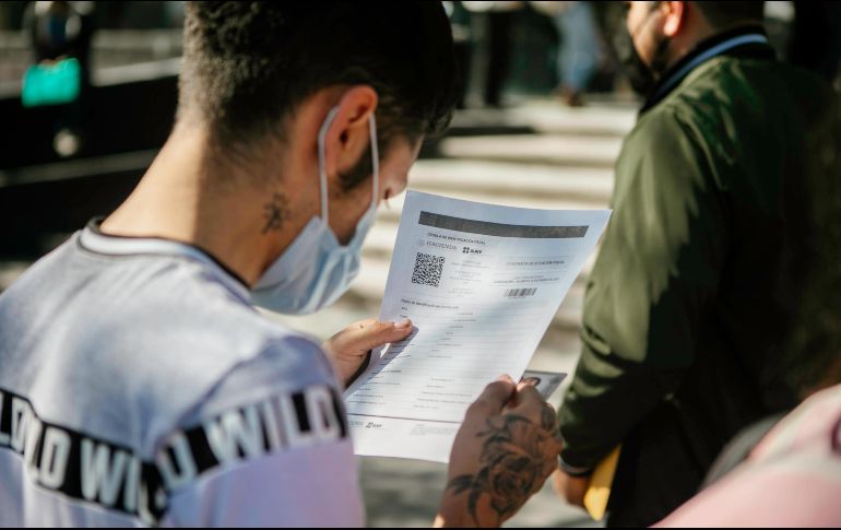 Un joven revisa su certificado de vacunación, obligatorio en Jalisco para entrar a eventos masivos. EL INFORMADOR/G. Gallo