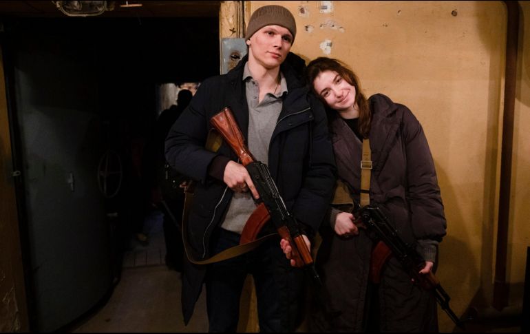 Una pareja de jóvenes se une a la defensa de Kiev y posan para la cámara con una sonrisa luego de recibir sus armas. EFE / M. Palinchak