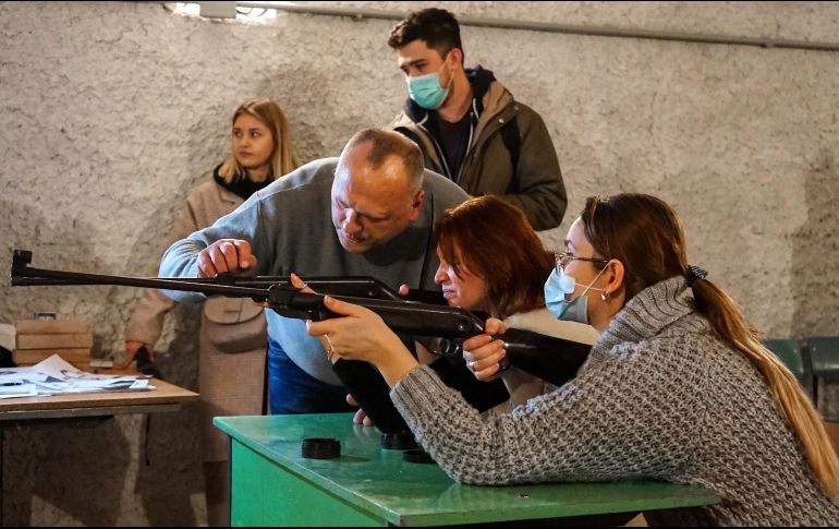 Un instructor muestra cómo disparar a dos civiles en la ciudad de Lviv, Ucrania. EFE / K. Salo