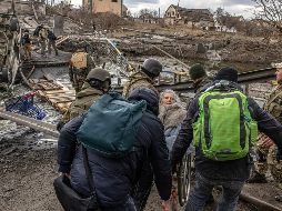 Soldados ucranianos y civiles cargan a una mujer de la tercera edad en un campo destruido por los enfrentamientos con Rusia. EF E/ R. Pilipey