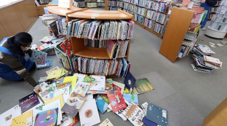 Empleados de una biblioteca en Koriyama acomodan libros que cayeron de los estantes durante el terremoto de este miércoles. EFE/JIJI PRESS
