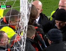 El aficionado, con una camisa naranja con el mensaje de su protesta, corrió hacia una de las porterías y ató su cuello al poste. ESPECIAL