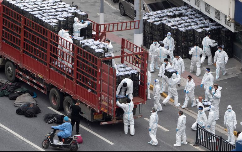 Trabajadores con equipo de protección descargan un camión de alimentos antes de que sean distribuidos entre la población de Shanghái. AP/CHINATOPIX