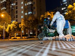 Repartidor de comida usa un traje de protección antes de entrar a una unidad habitacional. Shanghái ha sido sometida a algunas de las medidas más severas desde que el virus surgió. AP