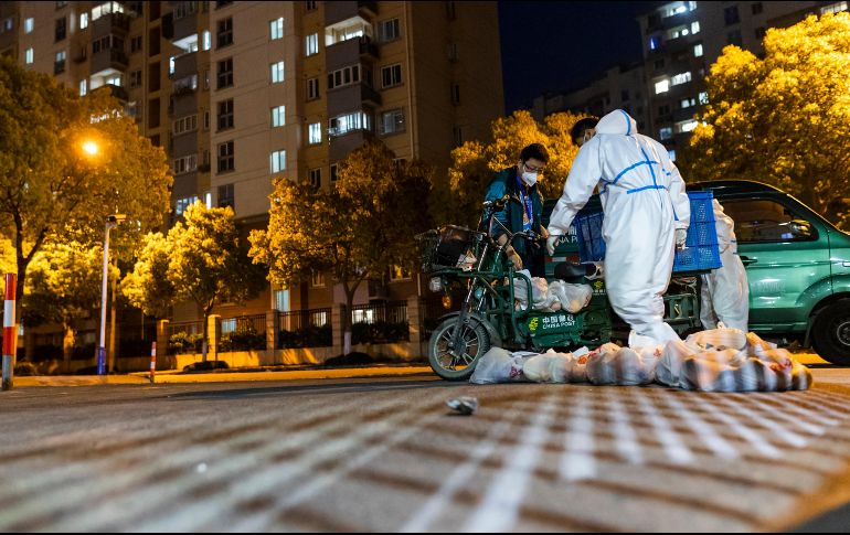Repartidor de comida usa un traje de protección antes de entrar a una unidad habitacional. Shanghái ha sido sometida a algunas de las medidas más severas desde que el virus surgió. AP