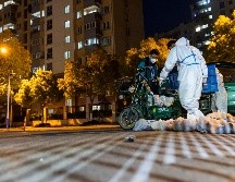 Repartidor de comida usa un traje de protección antes de entrar a una unidad habitacional. Shanghái ha sido sometida a algunas de las medidas más severas desde que el virus surgió. AP