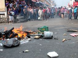 Los migrantes comenzaron el fuego al prender una silla de madera, así como artículos de plástico y rejas de madera al tiempo que exigían a los comerciantes y personas que se encontraban comprando continuar su camino.EFE / J. Blanco