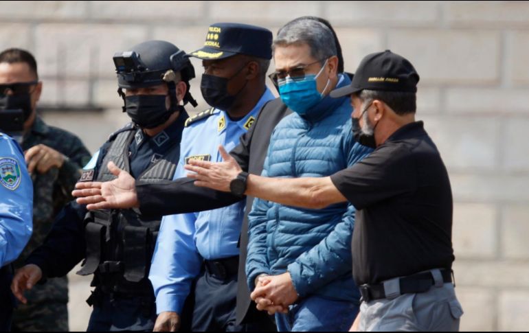 Juan Orlando Hernández acompañado por elementos de seguridad en su extradición. EFE/H. Espinoza