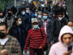 Personas protegidas con cubrebocas caminan por una calle de Santiago, en Chile. XINHUA/J. Villegas