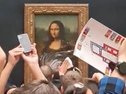Aunque no hay imágenes del momento en que hombre lanza la tarta, las instantáneas de los visitantes permiten ver al personal del Louvre recogiendo los restos. AP