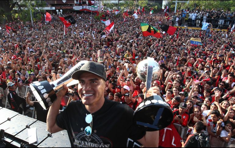 Aldo Rocha posa para la foto con ambos trofeos conquistados en la Final y la afición de fondo. EL INFORMADOR/A. Camacho