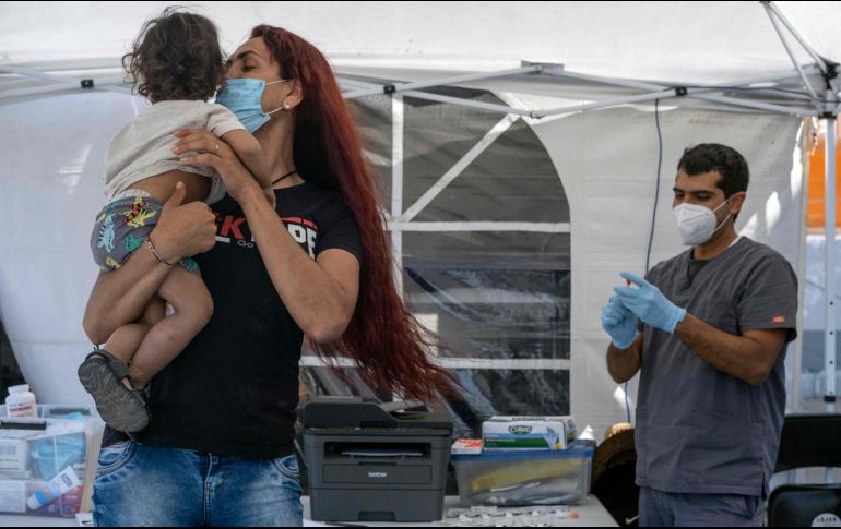 Una mujer calma a su hijo previo a la toma de muestras para detectar el COVID, en Tijuana. AFP/G. Arias
