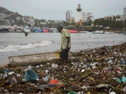 Un hombre permanece en la playa de Santa Lucía, en Acapulco, en medio de basura arrastrada por las lluvias que dejó 