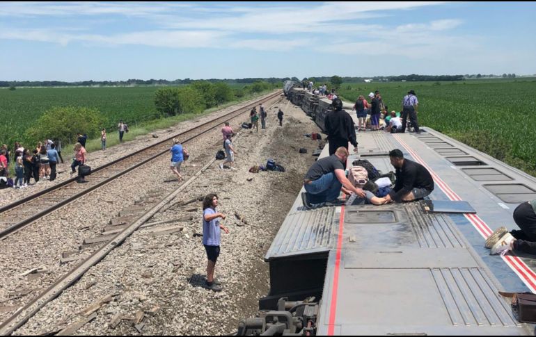 El tren fuera de las vías con varios vagones volcados de lado, personas encima auxiliando a los lesionados. AP/D. McDOnald