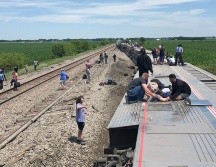 El tren fuera de las vías con varios vagones volcados de lado, personas encima auxiliando a los lesionados. AP/D. McDOnald