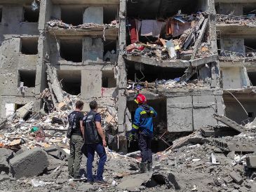 Equipos de rescate contemplan los escombros de un edificio derrumbado por misiles en una pausa de sus tareas. EFE