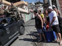 Un grupo de personas lleva en una cobija a una persona presuntamente muerta durante un operativo policial en la favela Alemão, al norte de Río de Janeiro. EFE/A. Coehlo