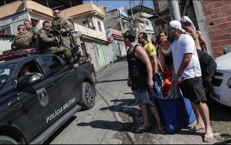 Un grupo de personas lleva en una cobija a una persona presuntamente muerta durante un operativo policial en la favela Alemão, al norte de Río de Janeiro. EFE/A. Coehlo