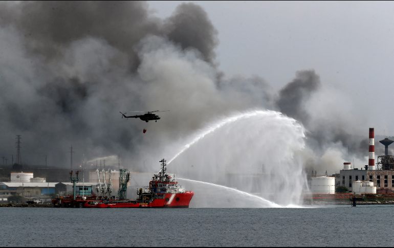 El buque Bourbon Artabaze, de la armada mexicana, lanzando un potente chorro de agua a unos 150 metros del fuego mientras que helicópteros dejan caer agua de mar. EFE / E. Mastrascusa