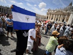 Una persona sostiene una bandera de Honduras en la plaza de San Pedro. AFP / F. Monteforte