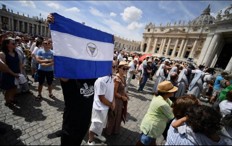 Una persona sostiene una bandera de Honduras en la plaza de San Pedro. AFP / F. Monteforte