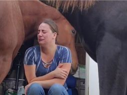 En el video se puede apreciar que la mujer se encuentra sentada en unas escaleras con un semblante triste en medio de dos caballos. ESPECIAL