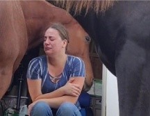 En el video se puede apreciar que la mujer se encuentra sentada en unas escaleras con un semblante triste en medio de dos caballos. ESPECIAL