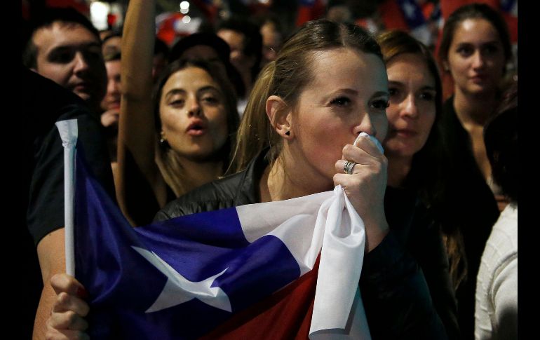 Una mujer besa la bandera chilena tras el rechazo a la nueva constitución. AFP