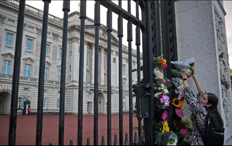 Una mujer deja un arreglo floral afuera del Palacio de Buckingham luego de que se anunciara la muerte de la reina Isabel II. AFP / D. Leal