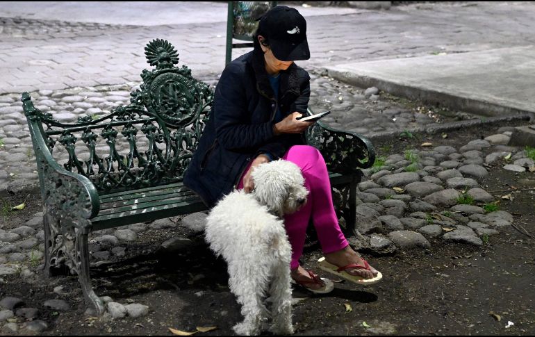Una mujer permanece sentada junto a su perro luego de que saliera de su hogar en Tlatelolco, en la Ciudad de México. AFP / A. Estrella