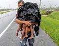 Un hombre carga a sus dos hijos, bajo la lluvia, luego de que el huracán "Ian" golpeara en Pinar de Río, en Cuba. AP / R. Espinosa
