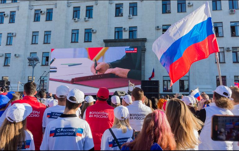 Personas con banderas rusas miran cómo Putin firma la anexión de las cuatro regiones ucranianas de Donetsk, Lugansk, Jersón y Zaporiyia, durante las celebraciones por el acontecimiento. AP